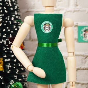 May include: A green dress with a white and green logo that says "Elfbucks Coffee".