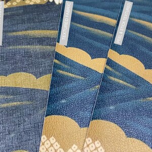Op de afbeelding: Vier voorbeelden van behang met een blauw en gouden patroon. De voorbeelden zijn gelabeld met "Peel & Stick Paper", "Fabric Non-Woven", "Textured Fabric" en "Peel & Stick Textured".