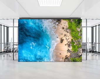 May include: An aerial view of a beach with turquoise water crashing on the shore. The beach is sandy with rocks and green vegetation.