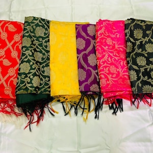 May include: A collection of colorful scarves with floral patterns and fringe. The scarves are in shades of red, green, yellow, purple, pink, and black. Each scarf has a different floral design in gold.