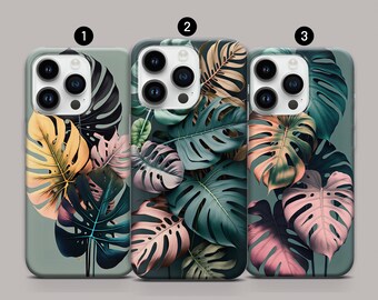 May include: Three phone cases with a tropical leaf design. The cases are green, pink, and yellow with a gray background.
