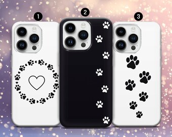 May include: Three phone cases with paw print designs. One white case has a heart surrounded by paw prints. A black case features white paw prints. Another white case displays black paw prints. These cases are for smartphones.