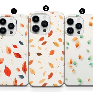 Puede incluir: Tres fundas para iPhone con diferentes diseños de hojas de otoño. La primera funda presenta un fondo blanco con hojas rojas, naranjas y amarillas. La segunda funda presenta un fondo blanco con hojas naranjas y amarillas. La tercera funda presenta un fondo blanco con hojas verdes y naranjas.