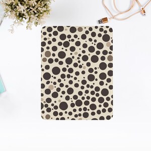 May include: A beige and brown patterned e-reader cover with a repeating pattern of circles.