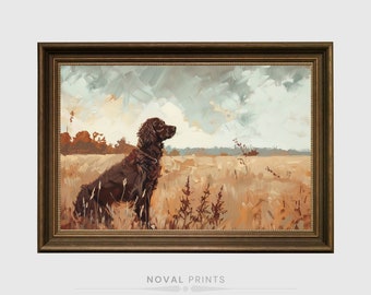 Op de afbeelding: Een ingelijst schilderij van een bruine hond die in een veld met hoog gras zit. De hond kijkt naar rechts en de lucht is lichtblauw met witte wolken. Het schilderij is in een bruine lijst met gouden accenten.