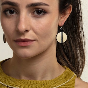 May include: A pair of white and black striped round earrings with a black bead accent.