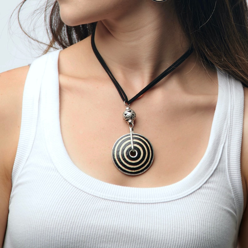 May include: A black and white striped pendant necklace with a silver bead and a black cord.