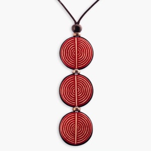 May include: A red necklace with three round pendants. Each pendant has a white concentric circle design.