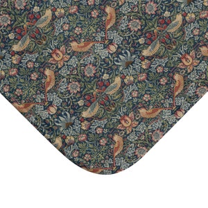 Op de afbeelding: Een blauwe stof met een herhalend patroon van gestileerde vogels, bloemen en bladeren. De vogels zijn lichtbruin van kleur met een gele snavel en een donkerbruin oog. De bloemen zijn roze en wit met een gele kern. De bladeren zijn groen en bruin.