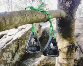May include: Two black triangle-shaped climbing holds with a green rope attached to a tree branch.