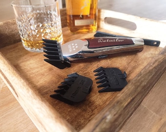 May include: A silver and red electric hair clipper with the word "Detailer" printed on the side. The clipper is on a wooden tray with two black plastic comb attachments. The comb attachments have the words "1 mm" and "3 mm" printed on them.