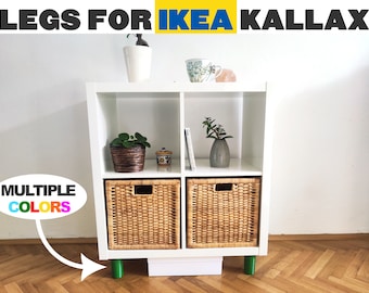 May include: White IKEA KALLAX shelf unit with green legs. The shelf has two wicker baskets, a potted plant, a book, and a small decorative object. The text "LEGS FOR IKEA KALLAX" is at the top of the image. The text "MULTIPLE COLORS" is in a speech bubble with rainbow colors.