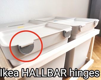 May include: Two white plastic bins with gray hinges. The bins are stacked on a wooden frame. The bins are labeled "IKEA HALLBAR hinges".