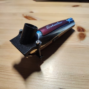 以下が含まれることがあります： 黒い掃除機アタッチメントが付いた銀と赤の電気バリカン。バリカンには「Detailer」という文字が側面に印刷されています。