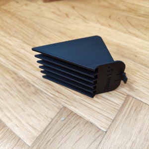 May include: Black plastic hair clipper guard with a comb attachment. The guard has a label that reads "38mm 1.5".
