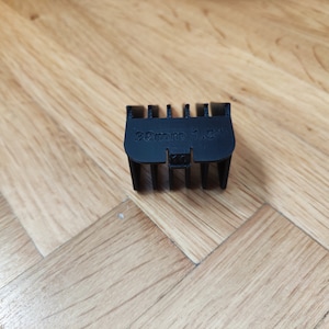 May include: Black plastic hair clipper guard with the text "32mm 1.5"" printed on it.