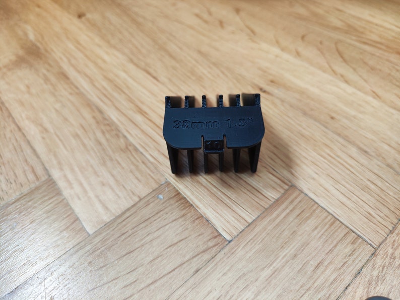 May include: Black plastic hair clipper guard with the text "32mm 1.5"" printed on it.