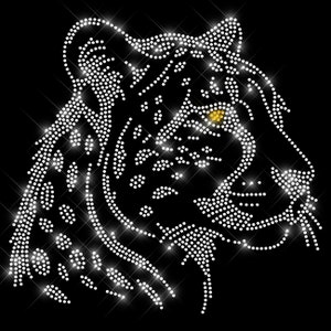 Könnte beinhalten: Ein weißes Tigerkopf-Design aus Strasssteinen, mit einem gelben Strassstein für das Auge. Das Design ist auf schwarzem Hintergrund.