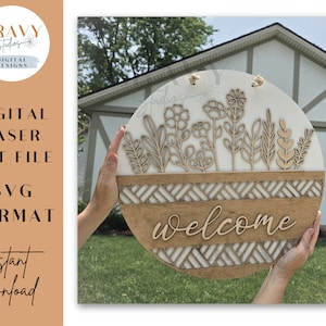 May include: A white and brown wooden round welcome sign with a geometric pattern and floral design. The sign says "welcome" in a cursive font.