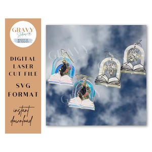 May include: A set of three digital laser cut file earrings in SVG format. The earrings feature a book with a rainbow arch and a small figure inside. The earrings are on a white background with a cloudy sky.