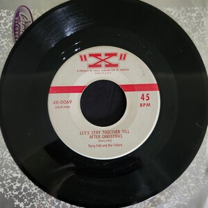 May include: A black vinyl record with a white label. The label has red text that reads "4X-0069 (EALW-4458)" and "45 RPM". The title of the song is "Let's Stay Together Till After Christmas (Terry Fell)" by "Terry Fell and the Fellers".