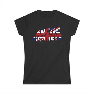 May include: Black t-shirt featuring the band name "Arctic Monkeys" in a stylized font. The text is filled with a Union Jack flag design, with red, white, and blue colors. The shirt has short sleeves and a crew neck.