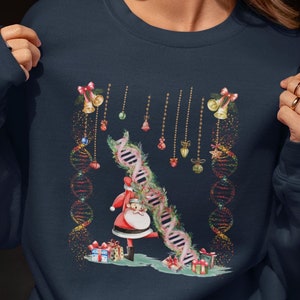 May include: A navy blue sweatshirt with a Christmas-themed design featuring Santa Claus climbing a DNA strand decorated with baubles and bells.
