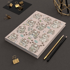 Peut inclure: Un journal rose clair avec un motif répété de chats de dessins animés portant des lunettes et tenant des hamburgers. Les chats sont entourés d'empreintes de pattes et d'illustrations de nourriture. Des crayons et des trombones dorés et noirs sont également visibles.