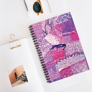 May include: A spiral bound notebook with a pink and purple abstract pattern. The pattern is made up of different microscope slides of tissue samples.