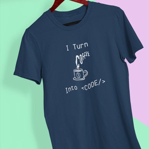 Może przedstawiać: Koszulka w kolorze granatowym z białym napisem "I Turn Coffee Into <CODE/>". Tekst jest stylizowany na kod. Mała ilustracja filiżanki kawy z parą unoszącą się nad nią znajduje się nad słowem "Coffee".