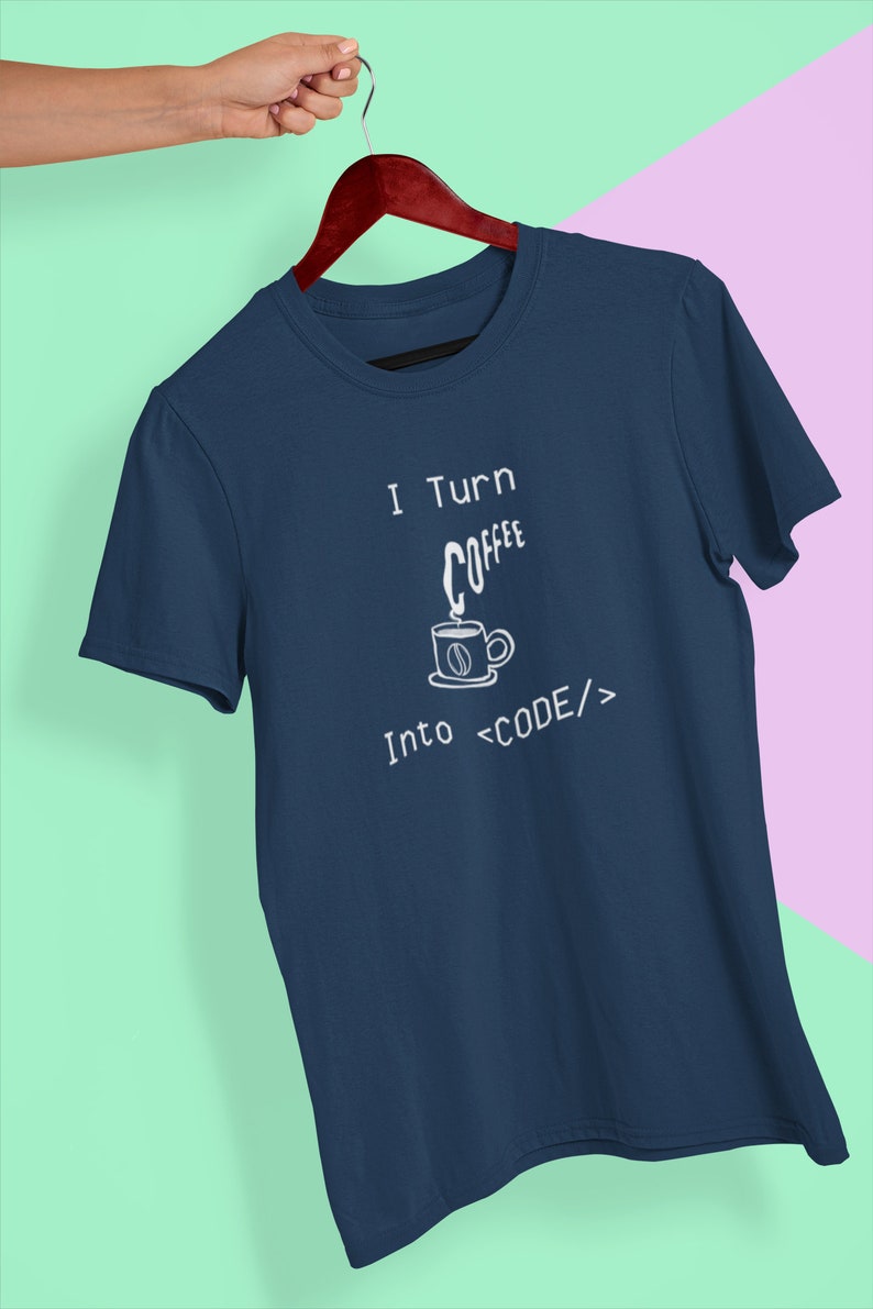Może przedstawiać: Koszulka w kolorze granatowym z białym napisem "I Turn Coffee Into <CODE/>". Tekst jest stylizowany na kod. Mała ilustracja filiżanki kawy z parą unoszącą się nad nią znajduje się nad słowem "Coffee".