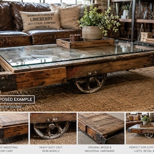 May include: A rectangular coffee table constructed from a repurposed industrial factory cart featuring weathered wood planks, heavy-duty cast iron wheels, and original metal hardware. The table includes a clear glass top and text reading REPURPOSED EXAMPLE.
