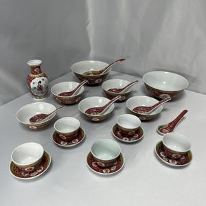 Peut inclure: Un ensemble de bols et de soucoupes en porcelaine rouge et blanche avec un motif floral. L'ensemble comprend un petit vase avec un motif floral.