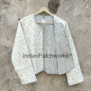May include: A white and green floral patterned jacket with a black and white striped lining. The jacket has a button closure and long sleeves.