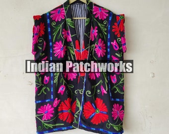 May include: A black sleeveless jacket with a floral embroidery pattern in shades of pink, red, green, and blue. The jacket has a white trim and a striped lining.