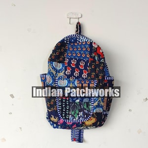 May include: A patchwork backpack with a variety of blue, red, and white floral patterns. The backpack has a flap pocket and a loop for hanging. The text "Indian Patchworks" is across the front.