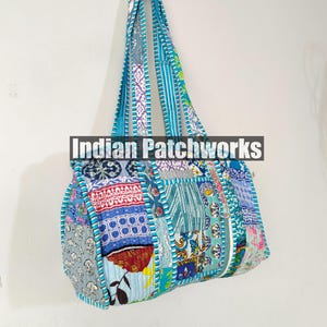 May include: A patchwork tote bag in various shades of blue, red, and white. The bag features a rectangular body with a rounded top and a matching blue strap. The text "Indian Patchworks" is across the center of the bag.