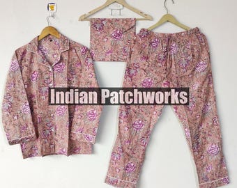 May include: A three-piece pajama set featuring a button-down shirt, pants, and a matching eye mask. The set is adorned with a floral pattern in shades of pink and purple. The text "Indian Patchworks" is visible.