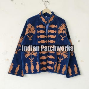 May include: A navy blue, long-sleeved top with a half-zip closure and a high collar. The top features a repeating pattern of orange floral and abstract shapes. The text "Indian Patchworks" is printed across the bottom of the image.