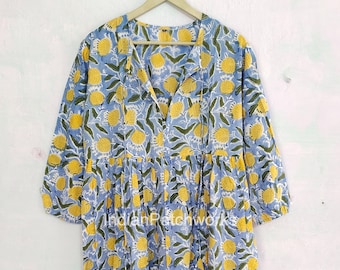 Può includere: Un abito in cotone con stampa floreale blu e gialla, scollo a V e maniche 3/4. L'abito ha una vita arricciata e una gonna fluida.