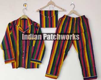 Peut inclure: Un ensemble de pyjama à rayures colorées, comprenant une chemise boutonnée, un pantalon et une petite pochette. L'ensemble présente des rayures verticales dans les tons de rouge, jaune, bleu et vert. La chemise et le pantalon sont bordés d'un passepoil blanc. Le texte "Indian Patchworks" est visible.