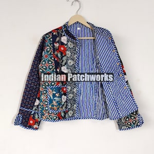 Puede incluir: Una chaqueta acolchada azul y blanca con un diseño de patchwork floral. La chaqueta tiene un cuello mandarín y mangas largas. El forro es de tela a rayas azul y blanca.