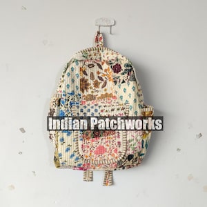 May include: A quilted backpack with a floral patchwork design. The backpack features a variety of colorful floral patterns on a cream background. The text "Indian Patchworks" is across the front of the bag.