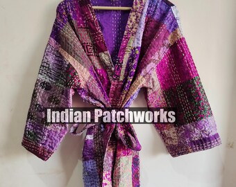 Op de afbeelding: Een paarse en roze patchwork-gequilte badjas met een strikceintuur. De badjas is gemaakt van kantha-stof en heeft een vintage uitstraling. "Indian Patchworks" is op de badjas gedrukt.