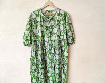 Può includere: Un vestito a fiori verde e bianco con maniche a 3/4 appeso a un appendiabiti in legno.