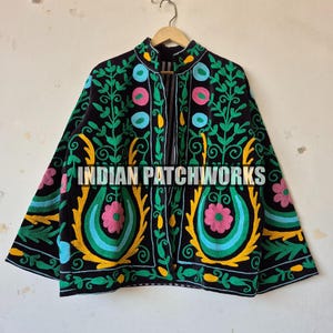 May include: Black jacket with colorful floral embroidery. The jacket features a high collar and is adorned with green, yellow, pink, and blue floral patterns. The text "INDIAN PATCHWORKS" is visible on the jacket.