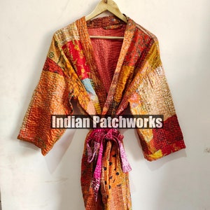 Op de afbeelding: Een kleurrijke patchwork kimono-jas met een strikceintuur. De jas is gemaakt van verschillende stoffen in tinten oranje, rood, geel en blauw. De tekst "Indian Patchworks" is op de jas gedrukt.