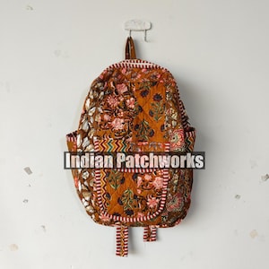 May include: A quilted backpack with a floral pattern in shades of brown, red, and white. The backpack has a rectangular pocket and straps. The text "Indian Patchworks" is across the front.