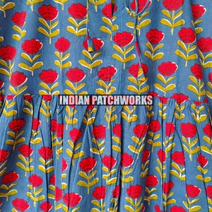 May include: Close-up of a blue fabric with a repeating floral pattern. Red flowers with yellow stems and green leaves are printed on the fabric. The text "INDIAN PATCHWORKS" is printed across the fabric.