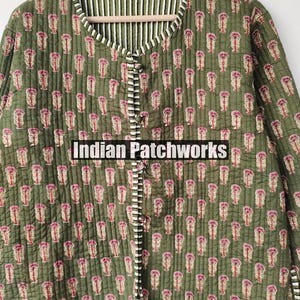 May include: Olive green quilted jacket with a floral pattern in pink and beige. The jacket features a striped lining and trim, with a button-up front. The text "Indian Patchworks" is visible on the front.